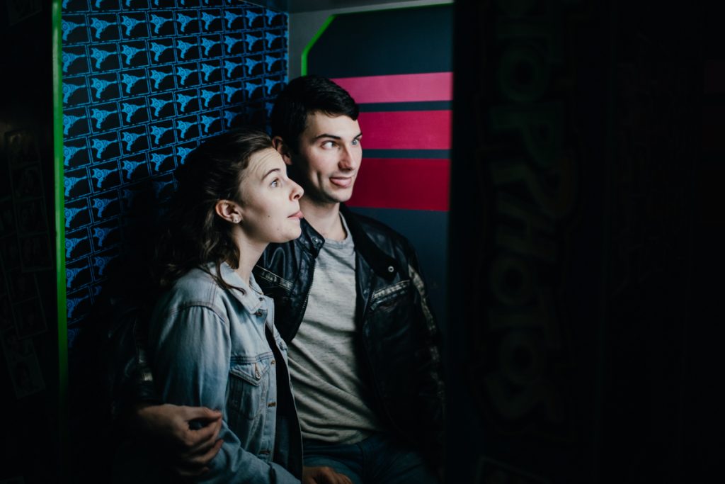 Couple recreating their first date making silly faces in a photobooth.
