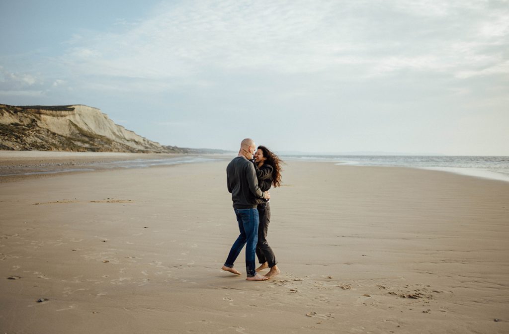 Couple dancing together on a wide open beach.